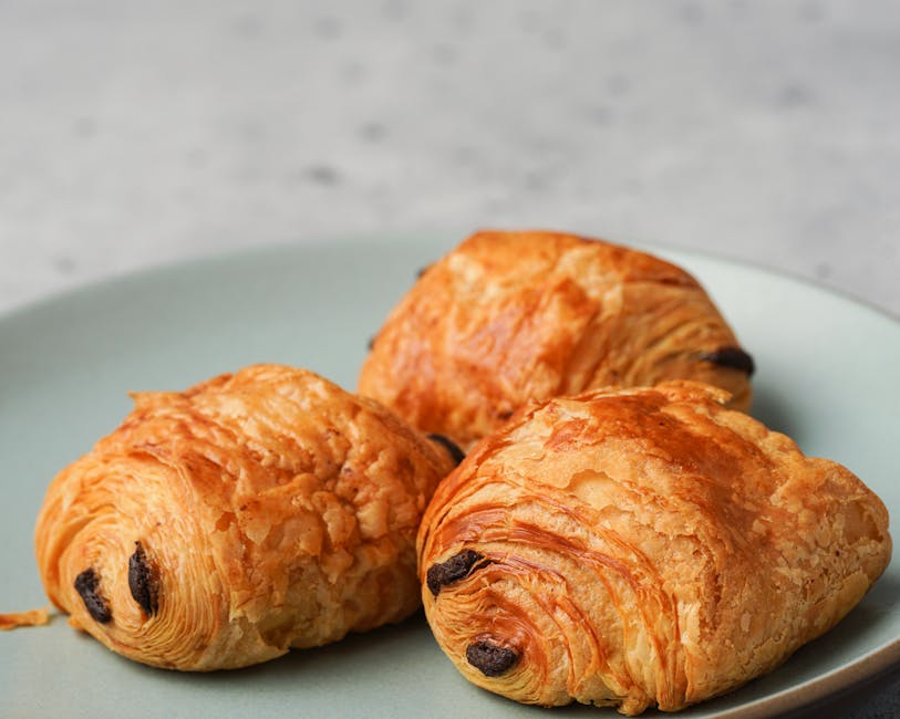 Pain au chocolat feuilleté doré servi sur une assiette