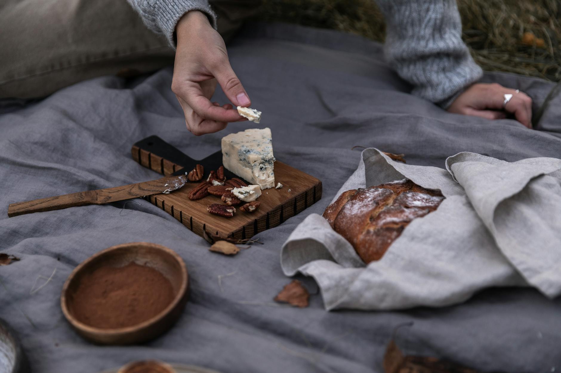 Pain de seigle aux noix sur une planche en bois avec couteau et fromages